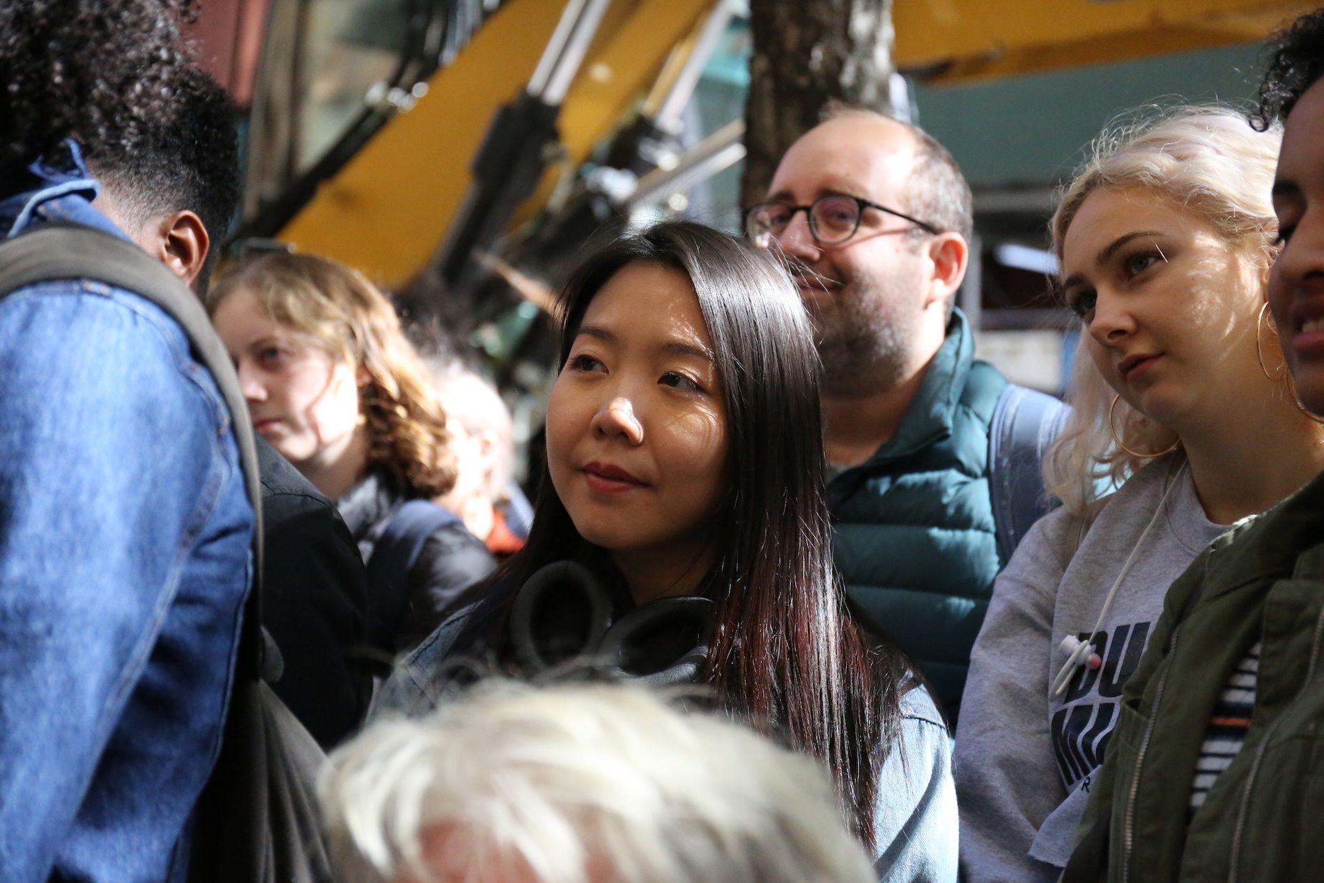 Dark haired Asian woman looks on at Ross Gay's reading